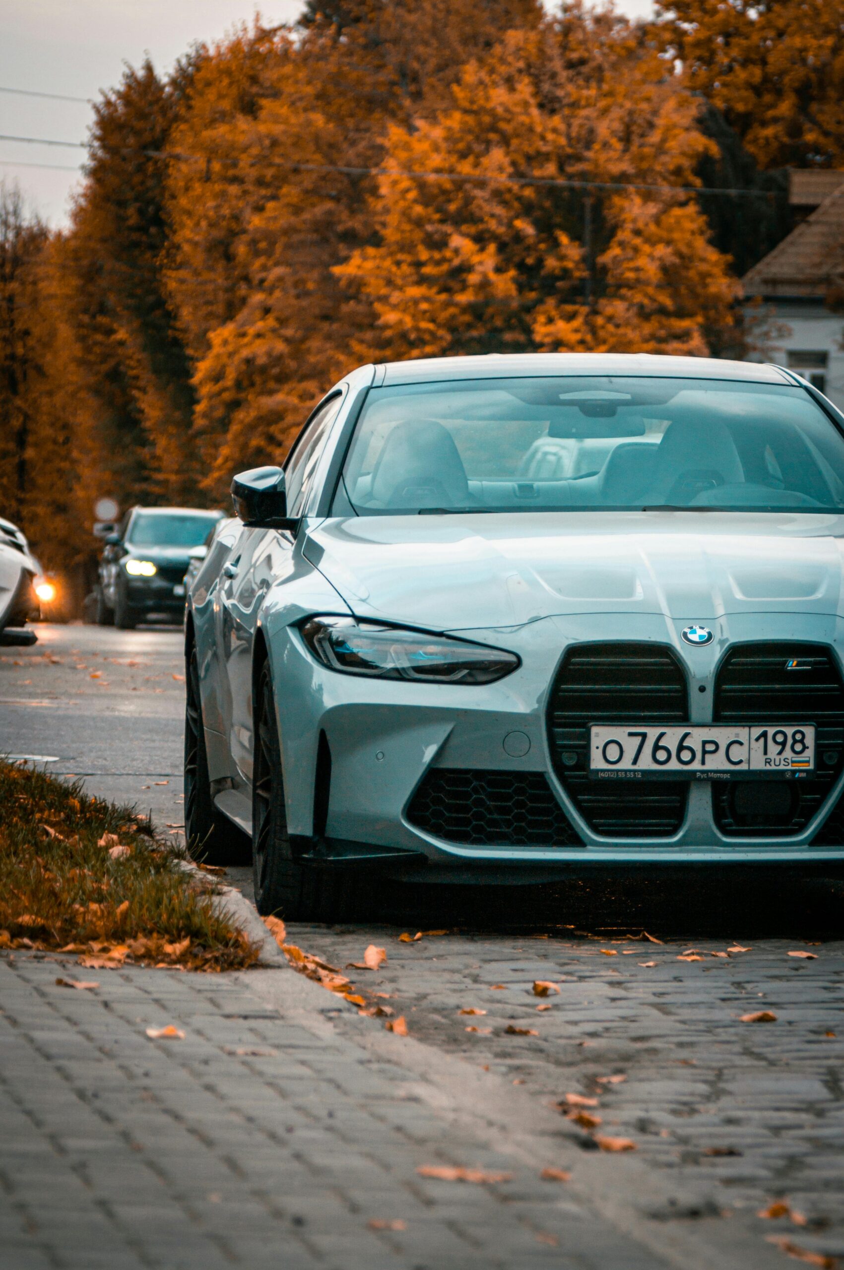 Luxurious BMW car parked on an autumn road in Kaliningrad, surrounded by vibrant fall foliage.