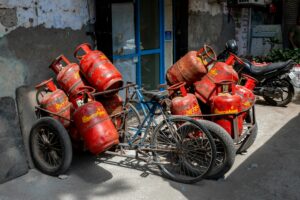 A street in Mumbai featuring a bicycle cart loaded with red gas cylinders, showcasing urban daily life.